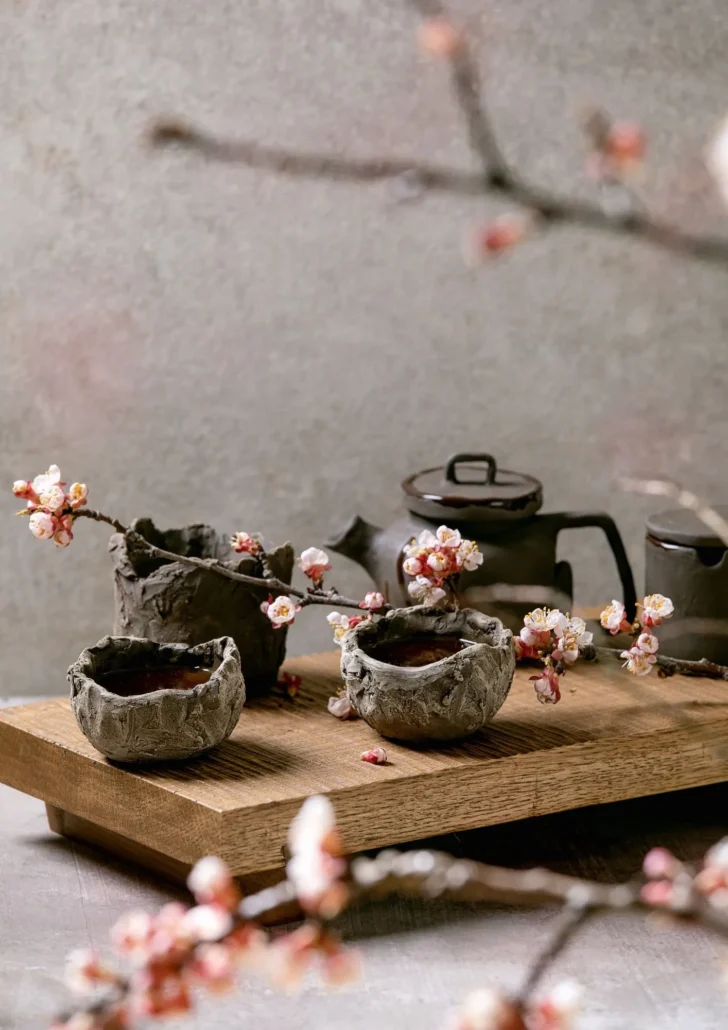 Wabi-sabi stílusú japán teaszertartás szabálytalan kerámiacsészékkel és cseresznyevirággal